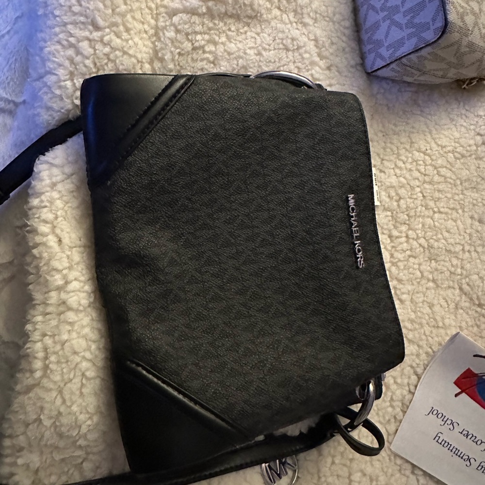 Black logo Michael Kors one zip center plus two snap close sections.